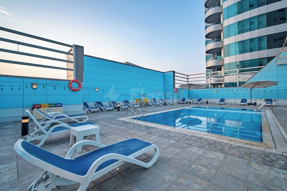 Outdoor pool area at Copthorne Hotel Sharjah, Sharjah, with blue lounge chairs and turquoise tiled walls
