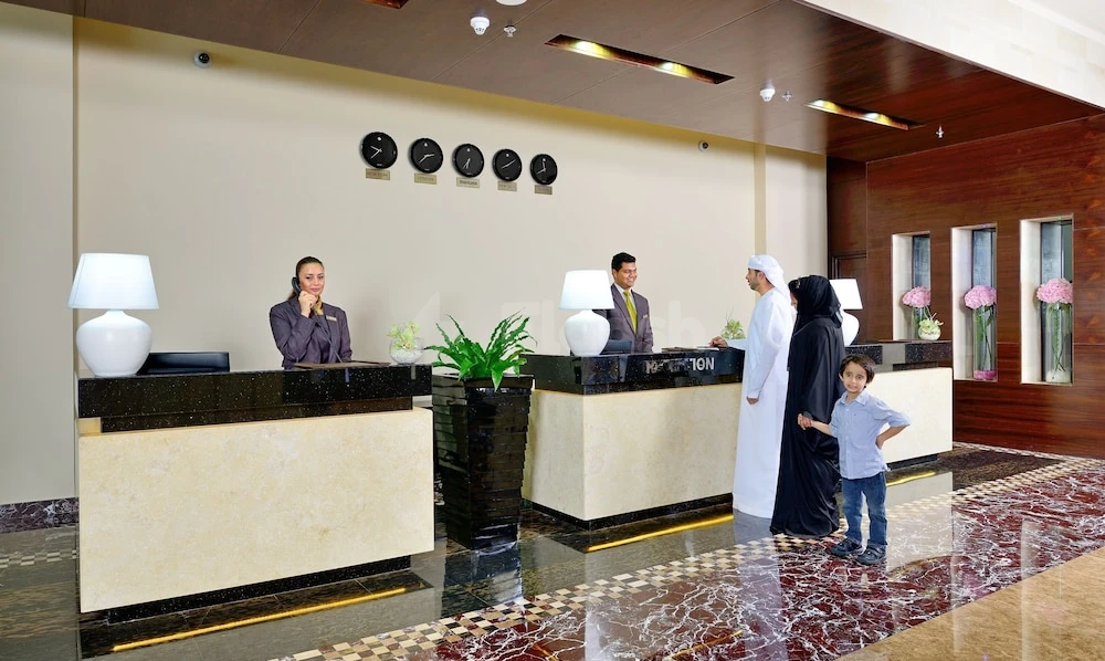 Reception area at Copthorne Hotel Sharjah, featuring marble floors and wall clocks above the desk